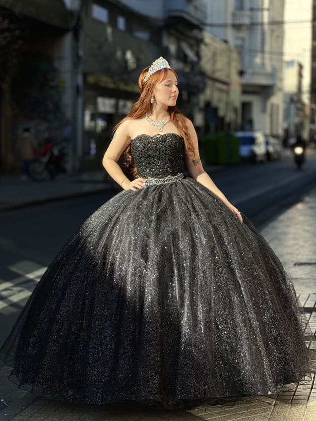Vestido de 15 negro con brillo, falda amplia estilo princesa y corset strapless bordado, usado en exterior urbano.