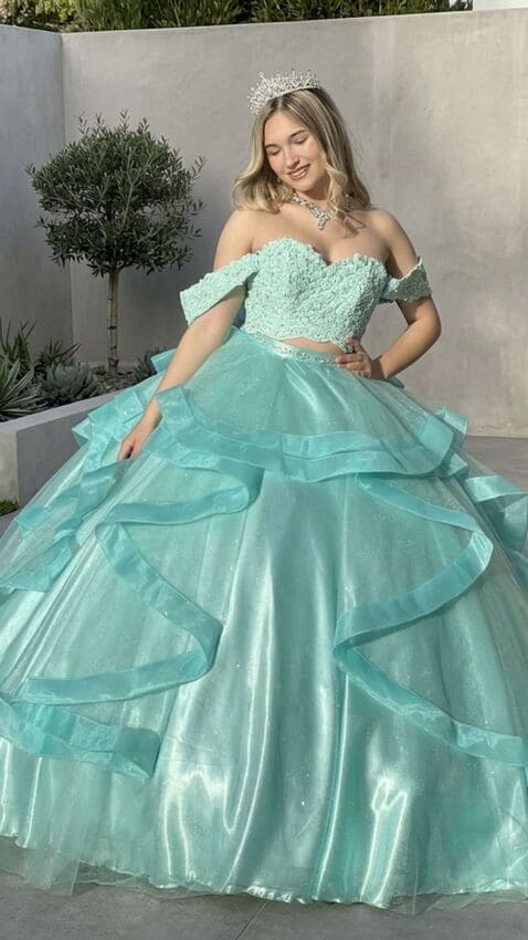 Vestido de 15 verde agua estilo princesa con corset off shoulder bordado y falda amplia con volados de tul, lucido en exterior urbano.