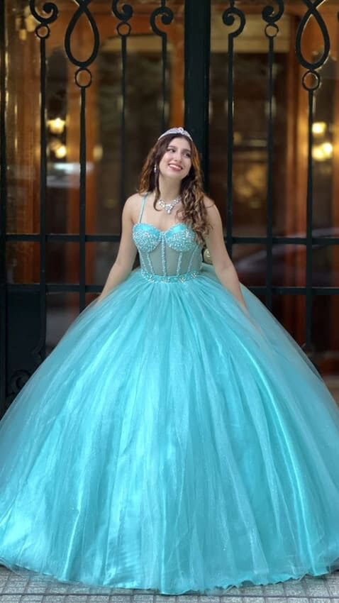 Vestido de quince celeste estilo princesa con corset bordado con breteles y falda amplia de tul, lucido en entrada elegante con rejas de fondo.